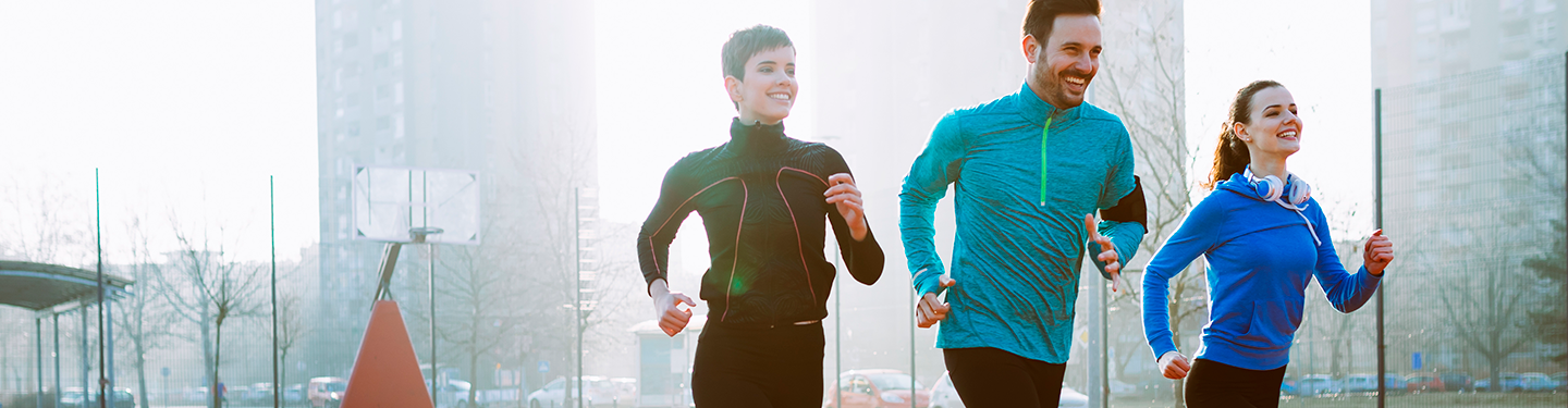 Grupo de tres personas corriendo por la calle en invierno