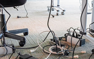 Muchos cables conectados a enchufes debajo de un puesto de trabajo